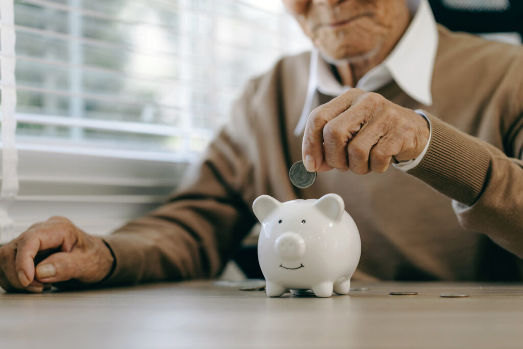 pension man saving money putting it into a piggy bank